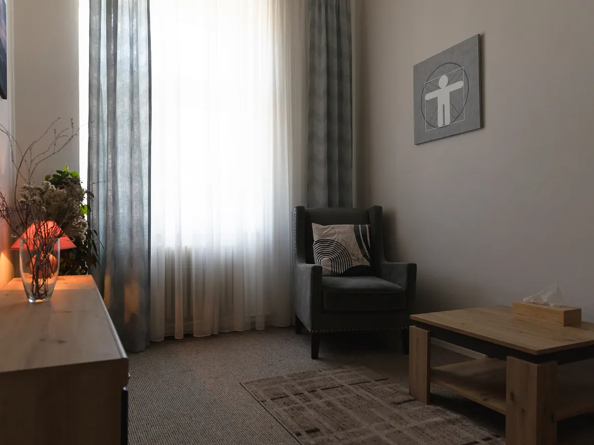 Terapeutická místnost s oknem, křeslem a stolkem